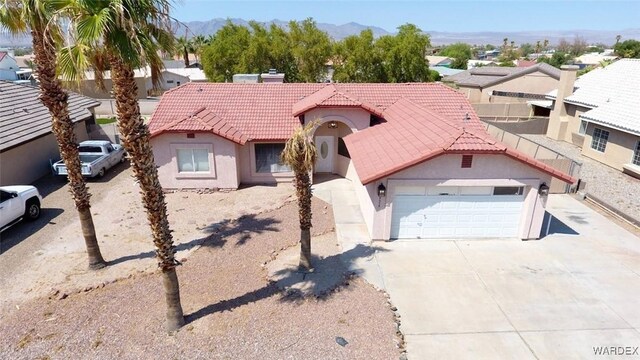 mediterranean / spanish home featuring concrete driveway, a tile roof, an attached garage, a mountain view, and stucco siding