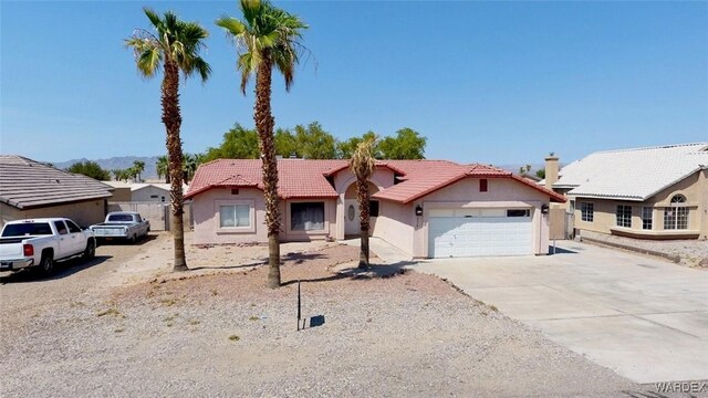 view of front of home with a garage, a tiled roof, concrete driveway, and stucco siding