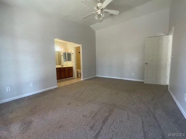 unfurnished bedroom featuring baseboards, connected bathroom, ceiling fan, vaulted ceiling, and carpet floors