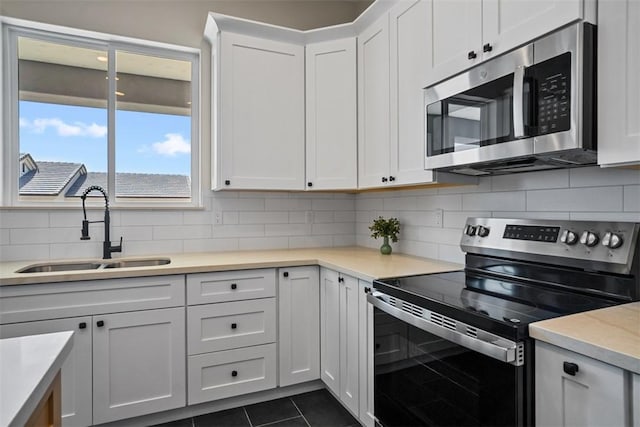 6068 S Greenhorn Dr, Fort Mohave, AZ 86426 - kitchen with stainless steel appliances, a sink, dark tile patterned floors, and white cabinetry