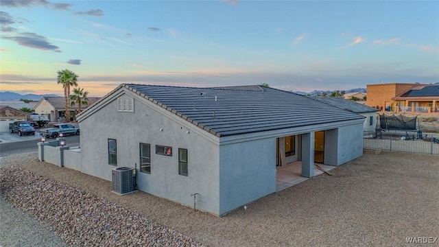 6068 S Greenhorn Dr, Fort Mohave, AZ 86426 - back of house at dusk with central air condition unit, stucco siding, a tile roof, and a residential view