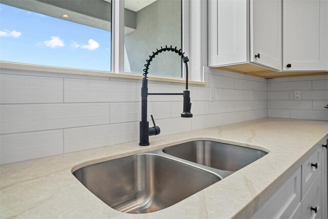 6068 S Greenhorn Dr, Fort Mohave, AZ 86426 - kitchen view of a sink, tasteful backsplash, light stone countertops, and white cabinetry