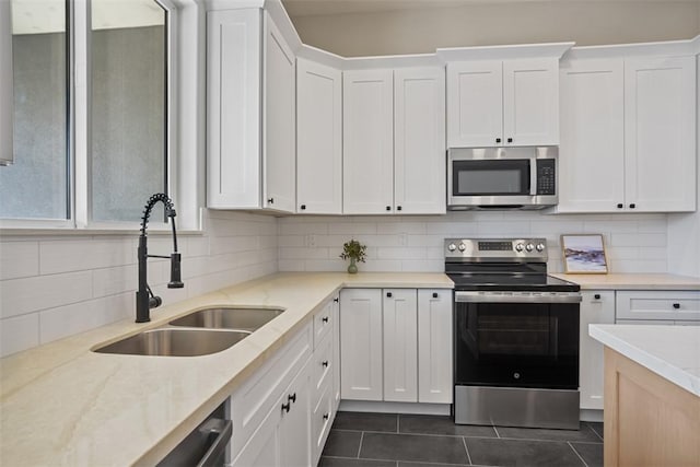 6068 S Greenhorn Dr, Fort Mohave, AZ 86426 - kitchen with appliances with stainless steel finishes, a sink, decorative backsplash, dark tile patterned floors, and white cabinetry