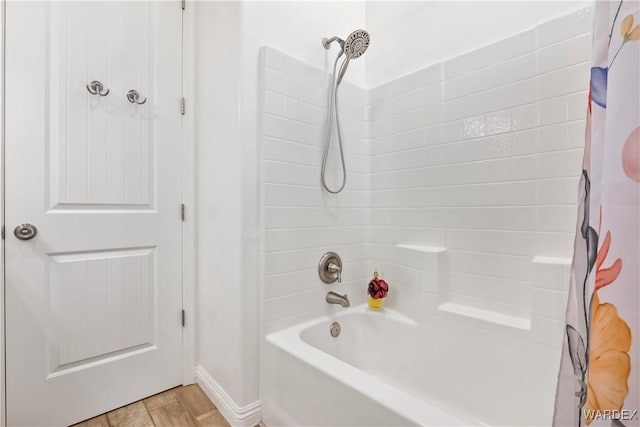 bathroom featuring wood finished floors, baseboards, and shower / bath combo with shower curtain