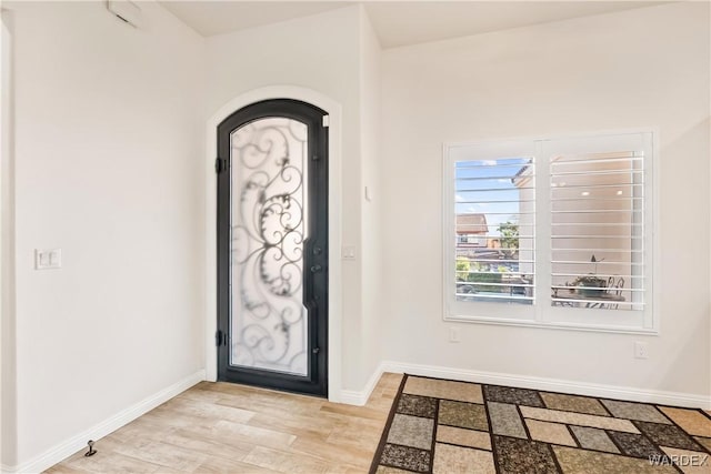 entrance foyer with light wood-style flooring, baseboards, and arched walkways