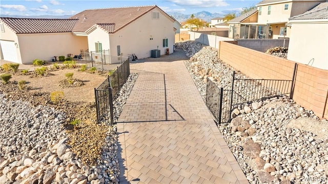 view of property exterior with central AC unit, a fenced backyard, a tiled roof, and stucco siding