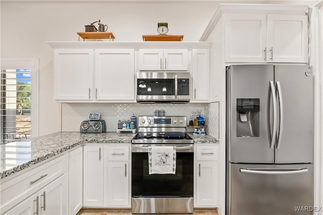 kitchen featuring stainless steel appliances, white cabinets, and backsplash