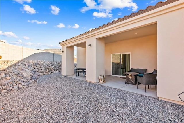 rear view of property featuring a patio, fence, and stucco siding