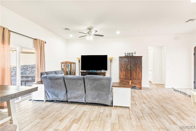 living room featuring light wood-style flooring, visible vents, and ceiling fan