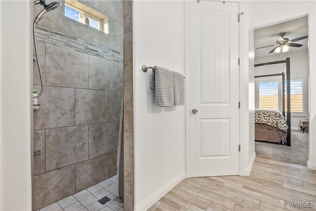 full bathroom with baseboards, a tile shower, wood finished floors, and ensuite bathroom