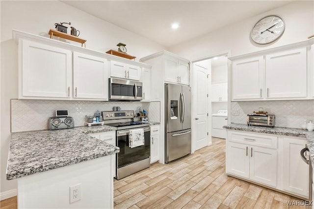 kitchen featuring light wood finished floors, white cabinets, washer / clothes dryer, light stone counters, and stainless steel appliances