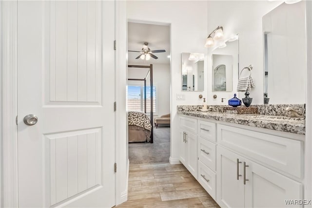 ensuite bathroom with ensuite bathroom, ceiling fan, wood finished floors, a sink, and double vanity