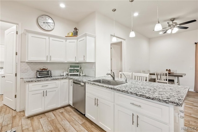 kitchen with white cabinets, dishwasher, decorative light fixtures, light wood-type flooring, and a sink