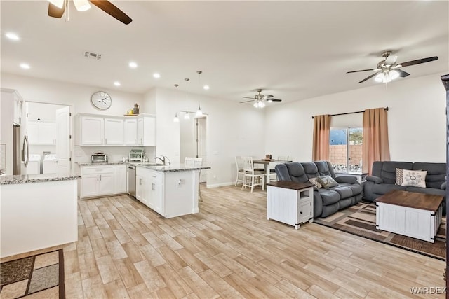 kitchen with white cabinets, open floor plan, hanging light fixtures, light stone countertops, and a peninsula