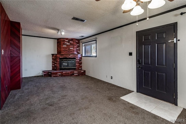 unfurnished living room featuring a fireplace, crown molding, carpet, and visible vents