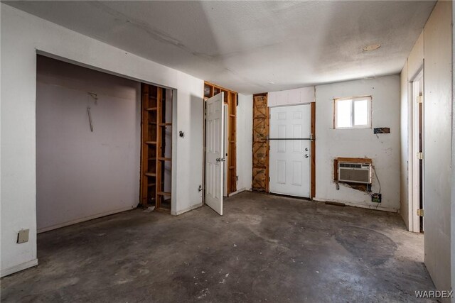 unfurnished bedroom featuring an AC wall unit and concrete flooring