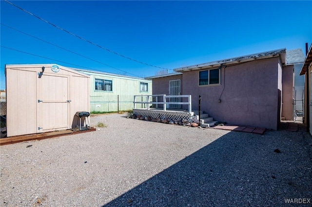 back of property featuring stucco siding, a storage shed, and an outdoor structure