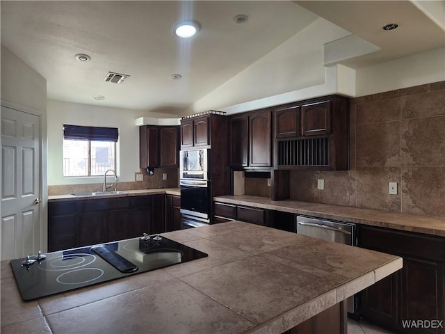 kitchen featuring stainless steel appliances, visible vents, decorative backsplash, a sink, and dark brown cabinets