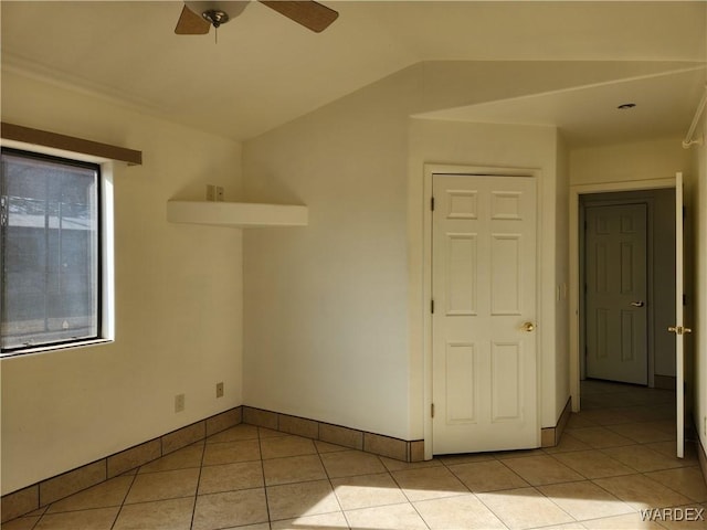 spare room with lofted ceiling, light tile patterned flooring, ceiling fan, and baseboards