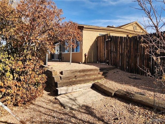 view of side of property featuring fence and stucco siding