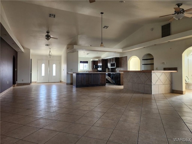 unfurnished living room featuring a ceiling fan, arched walkways, visible vents, and light tile patterned floors