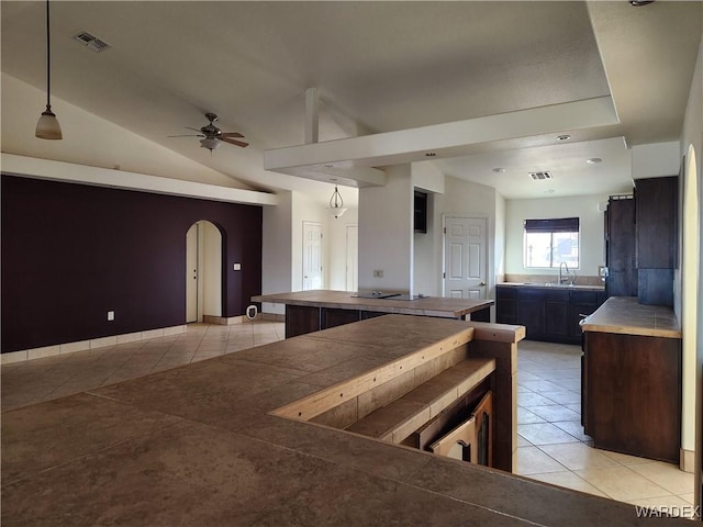 kitchen with light tile patterned floors, arched walkways, ceiling fan, hanging light fixtures, and a sink