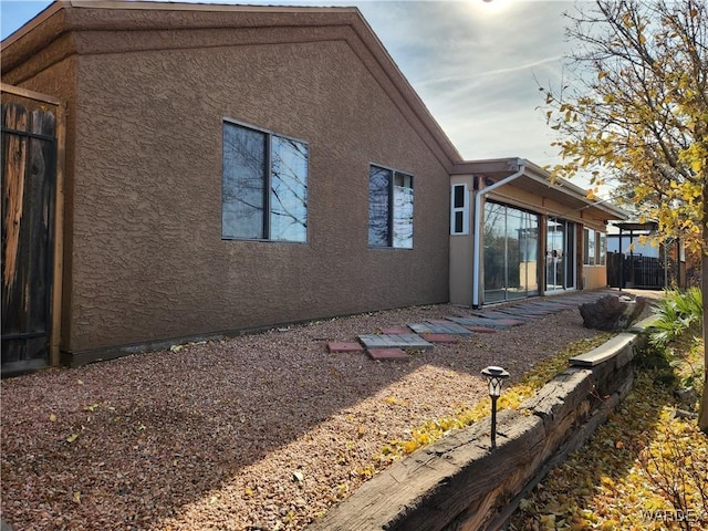 rear view of property featuring fence and stucco siding