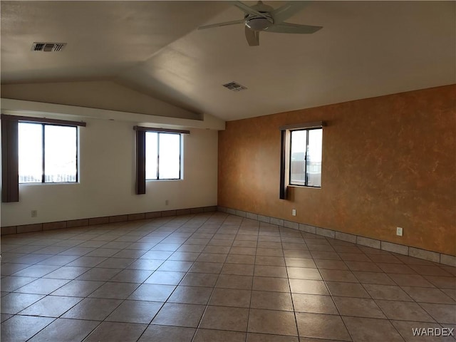 spare room featuring ceiling fan, visible vents, vaulted ceiling, and light tile patterned floors