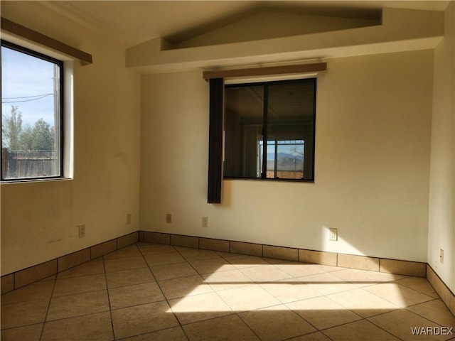 unfurnished room featuring lofted ceiling, light tile patterned flooring, and baseboards