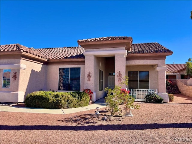 mediterranean / spanish home with a tiled roof, fence, and stucco siding