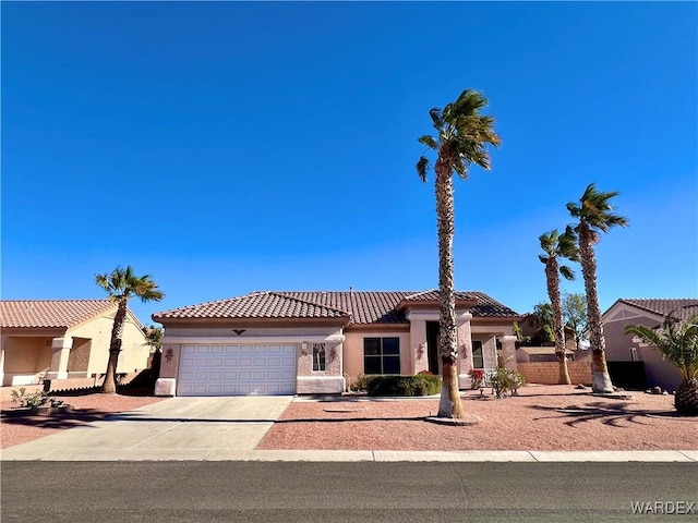 mediterranean / spanish house featuring a garage, concrete driveway, a tile roof, and stucco siding