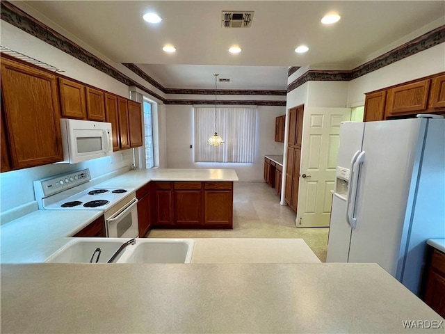 kitchen featuring decorative light fixtures, light countertops, visible vents, a sink, and white appliances