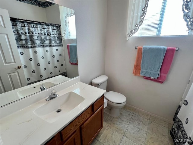 bathroom with toilet, marble finish floor, and vanity