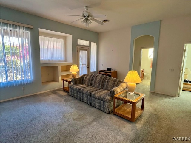 living room with carpet floors, baseboards, arched walkways, and a ceiling fan