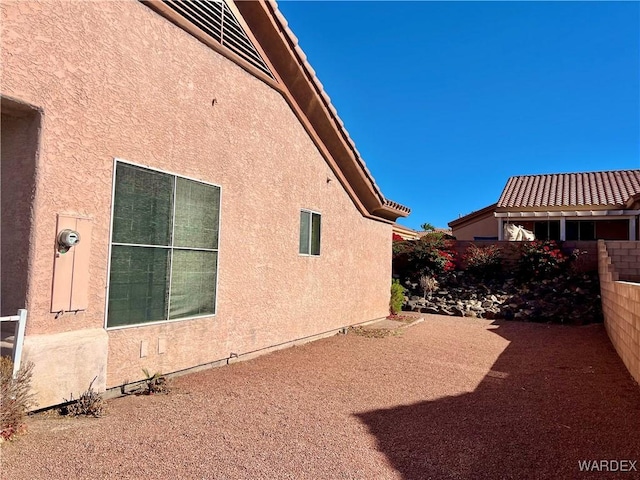 view of home's exterior with a patio area, fence, and stucco siding