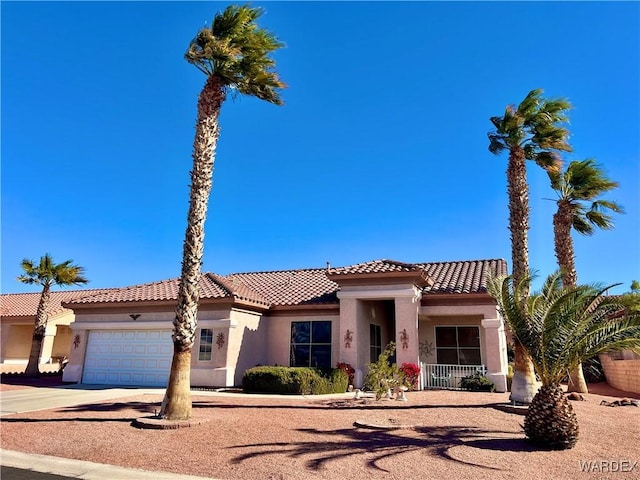 mediterranean / spanish-style house featuring an attached garage, a tiled roof, concrete driveway, and stucco siding