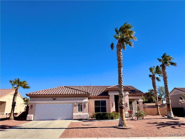 mediterranean / spanish-style home featuring concrete driveway, a tile roof, an attached garage, and stucco siding