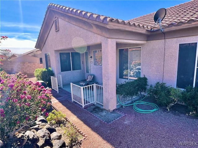 view of property exterior with fence, a tiled roof, and stucco siding