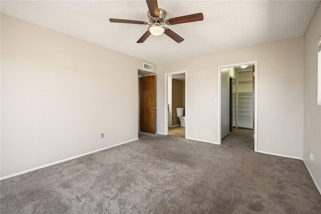 898 Crestwood Ln, Kingman, AZ 86409 - unfurnished bedroom with a walk in closet, carpet, a textured ceiling, ceiling fan, and ensuite bathroom