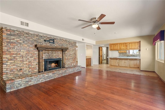 898 Crestwood Ln, Kingman, AZ 86409 - unfurnished living room featuring light wood-style floors, ceiling fan, and a brick fireplace