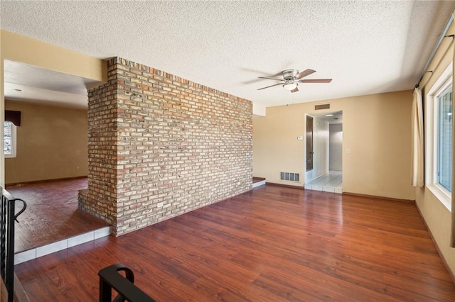898 Crestwood Ln, Kingman, AZ 86409 - unfurnished living room featuring ceiling fan, a textured ceiling, wood finished floors, and brick wall