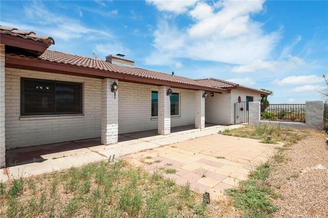 898 Crestwood Ln, Kingman, AZ 86409 - back of house featuring a chimney, a patio area, and brick siding
