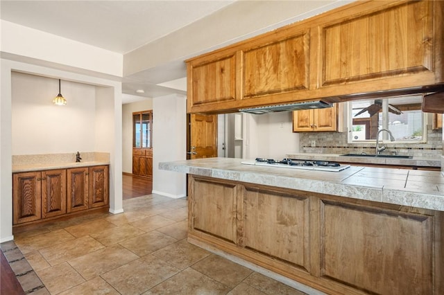 898 Crestwood Ln, Kingman, AZ 86409 - kitchen featuring white gas stovetop, backsplash, brown cabinetry, and healthy amount of natural light