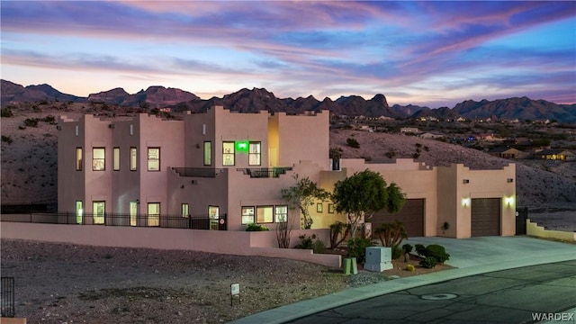 view of front of house featuring concrete driveway, fence, a mountain view, and stucco siding