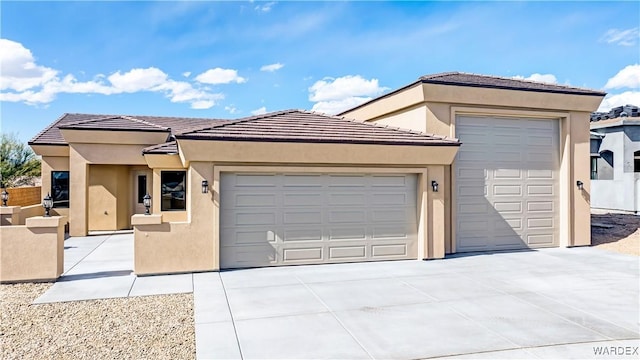 prairie-style house featuring a garage, driveway, a tiled roof, and stucco siding