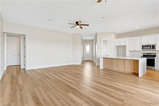 kitchen featuring open floor plan, stainless steel appliances, a ceiling fan, and light wood-style floors