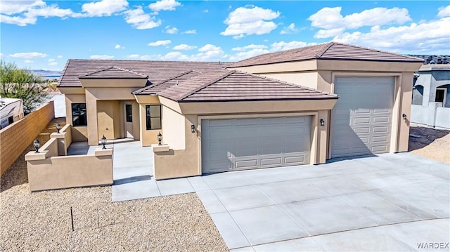 view of front of home with stucco siding, concrete driveway, fence, a garage, and a tiled roof