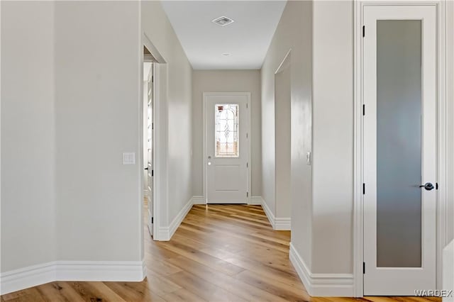 foyer featuring light wood-style floors, baseboards, and visible vents