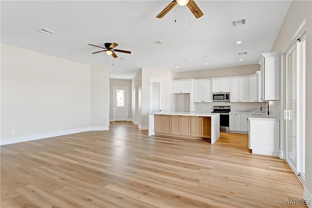 kitchen featuring open floor plan, stainless steel appliances, visible vents, and light wood-style floors