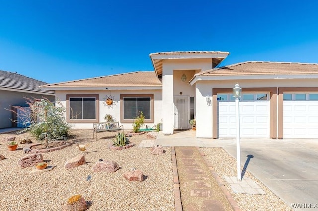 prairie-style home with a garage, a tile roof, concrete driveway, and stucco siding